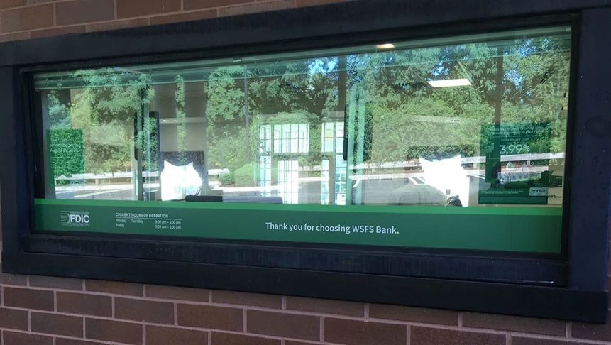 A customized WSFS Bank drivethru window graphic with branch hours of operation.
